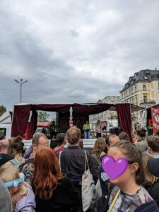 Zwei Rednerinnen von KritMed* auf einer Bühne, davor stehen viele Menschen