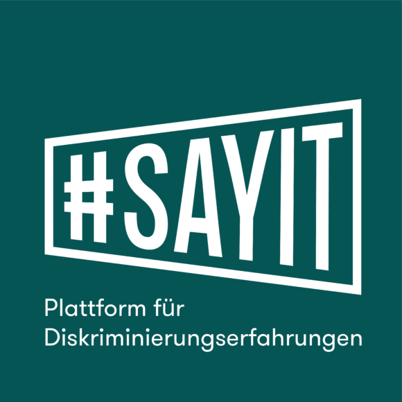 Zu sehen ist der umrahmte Schriftzug "#SAYIT" und klein dazu geschrieben "Plattform für Diskriminierungserfahrung".
